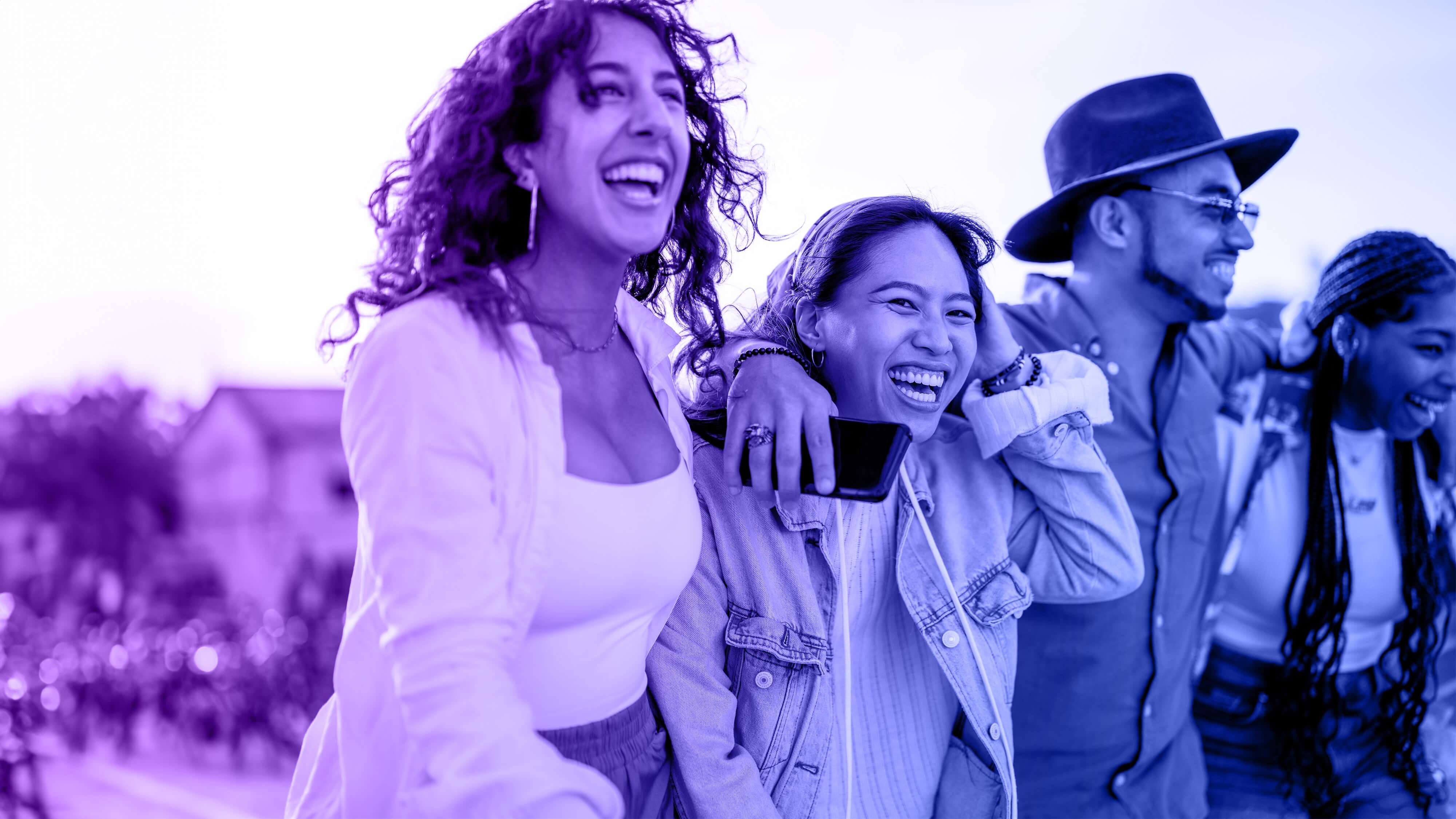 The image depicts four individuals standing closely together with their arms around each other, conveying a strong sense of camaraderie and connection.